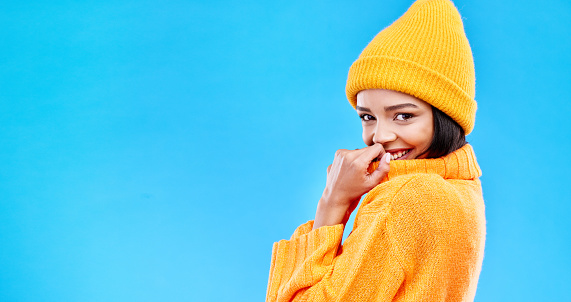 Happiness, excited and woman portrait with mockup in studio ready for cold weather with winter hat. Isolated, blue background and mock up with a happy young and gen z person with a smile and joy
