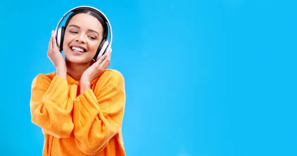 Photo of Music headphones, woman and smile on blue background, mockup studio and backdrop. Happy female, gen z model and listening to sound, streaming album and audio connection on media, mock up and podcast