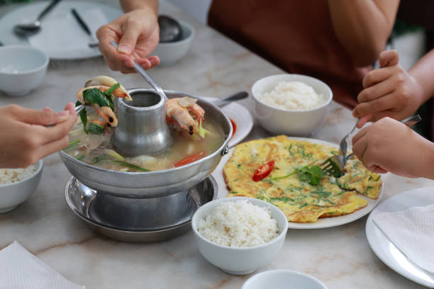 Close-up of tourists enjoying authentic Tom Yum Thai food with fragrant rice