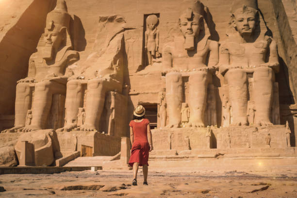 A young tourist in a red dress entering the Abu Simbel Temple in southern Egypt A young tourist in a red dress entering the Abu Simbel Temple in southern Egypt in Nubia next to Lake Nasser. Temple of Pharaoh Ramses II ramses i stock pictures, royalty-free photos & images