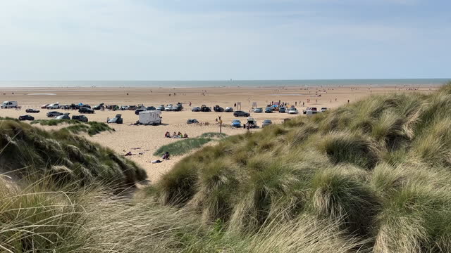 Cars and people on wide Ainsdale beach, view from dunes