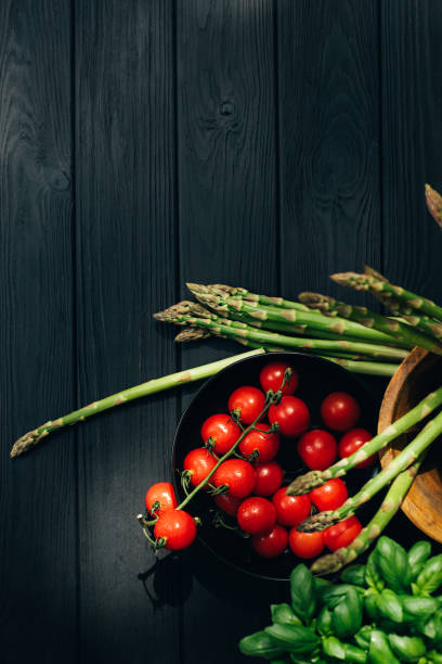 Set of green fresh vegetables, asparagus, cabbage, tomatoes, green salad, basilica on black wooden background