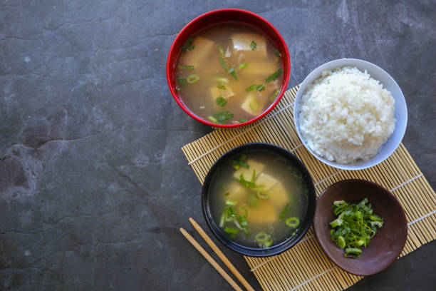 miso-suppe oder japanische miso-suppe in schüssel auf dem tisch. japanische küche in form von suppe mit dashi-zutaten, tofu, meeresfrüchten, gemüse und nach geschmack mit miso belegt - bamboo brown cooking gourmet stock-fotos und bilder