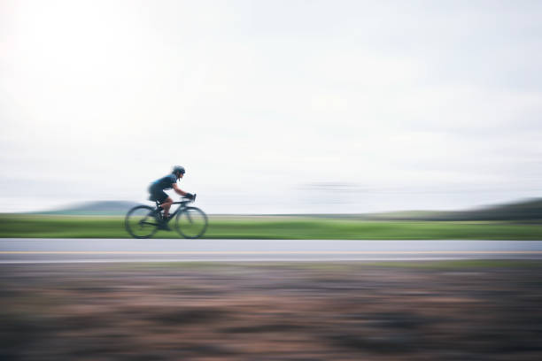 persona che pedala velocemente con motion blur, sky mockup e bici in campagna, triathlon e allenamento cardio. atleta, ciclismo e maratona con velocità, energia e sport per l'esercizio, la potenza o l'azione - endurance sport foto e immagini stock