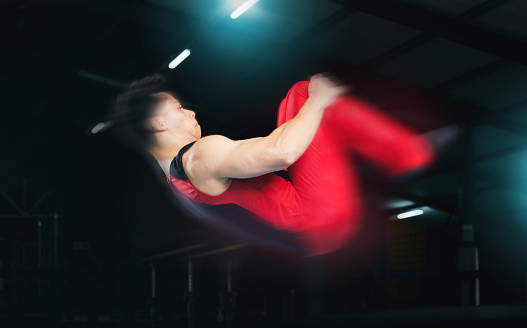 Training, gymnastics and jump with man in stadium for sports, speed and motion blur. Workout, action and challenge with flexible athlete in gym arena for performance, exercise and fitness health