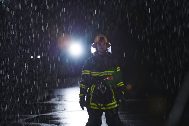 istock A determined female firefighter in a professional uniform striding through the dangerous, rainy night on a daring rescue mission, showcasing her unwavering bravery and commitment to saving lives. 1511333958