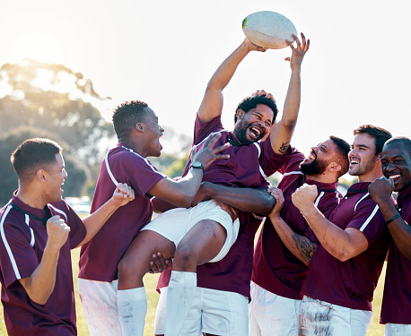 Sports, winner and rugby team with ball in celebration for winning match, game and sport competition. Fitness, teamwork and happy, excited athletes on field celebrate victory, success and motivation