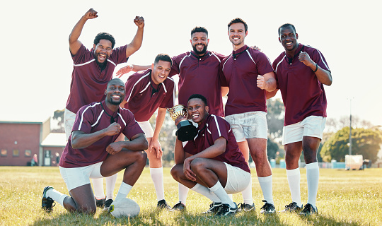 Sports, winner and rugby team with trophy in celebration for winning match, game and competition. Fitness, success and portrait of sport players celebrate victory, success and achievement on field