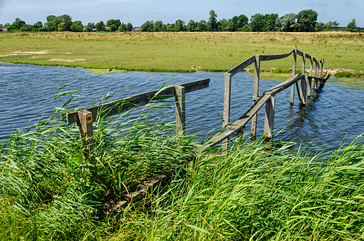 Old and somewhat shaky wooden footbridge across a creek in the polders between Rockanje and Tinte in the Netherlands