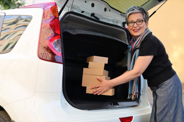 istock Happy mature woman loading purchases into car trunk. 1511382318