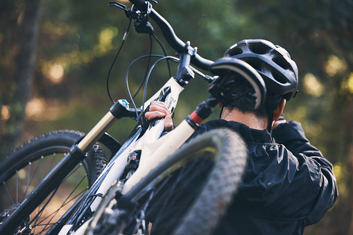 Bosque, fitness y hombre llevando bicicleta en la naturaleza con casco, sendero de aventura de ejercicio y mentalidad saludable. Ciclismo, maderas y ciclismo con bicicleta de montaña en los árboles para entrenamiento, motivación o energía. photo