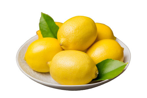 Fresh cutted lemon and whole lemons over round plate isolated on white background. Food and drink ingredients preparing. healthy eating theme top view with copy space.