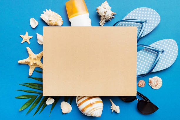 istock Summer time concept with blank greeting card and blank craft paper on colored background. Seashells from ocean shore in the shape of frame separated with space for text top view 1511420513