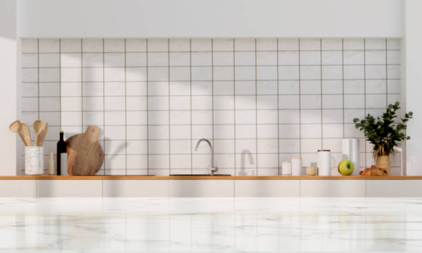 istock Stylish marble tabletop on wooden platform with copyspace at blurry kitchen utensils and dishes on light wall background. 3D render illustration 1511422163