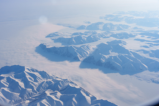 Snowy mountains and glaciers in the Arctic seen from an airplane
