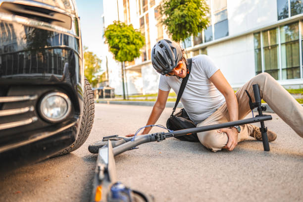 Man with protective helmet feeling knee pain after e-scooter riding accident