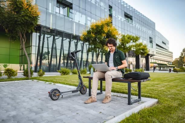 istock Men working on his laptop while sitting on a bench beside his electric scooter 1511474152