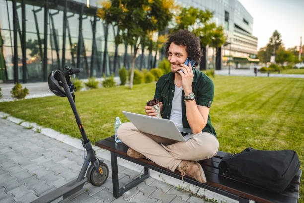 istock Men talking on the phone and drinking coffee while taking a break from working in public park 1511475194