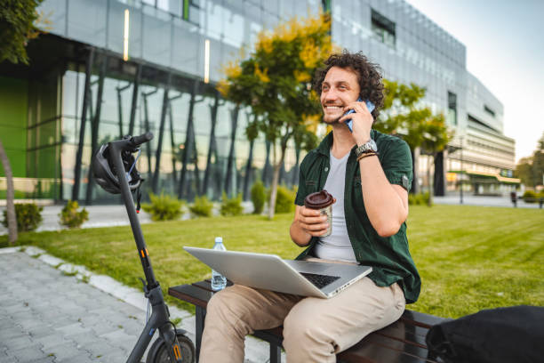 istock Men talking on the phone and drinking coffee while taking a break from working in public park 1511475736