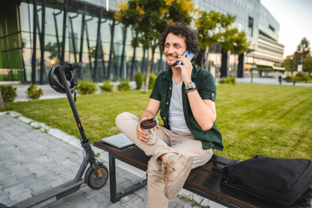 istock Men talking on the phone and drinking coffee while taking a break from working in public park 1511477843