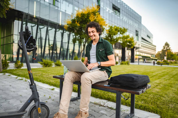 istock Men working on his laptop while sitting on a bench beside his electric scooter 1511478366