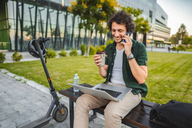 istock Men talking on the phone and drinking coffee while taking a break from working in public park 1511478379
