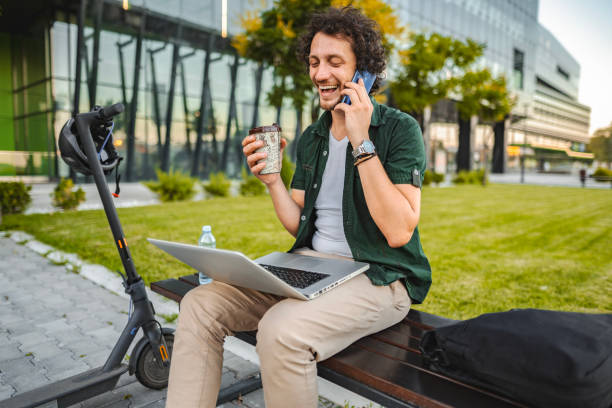 istock Men talking on the phone and drinking coffee while taking a break from working in public park 1511479464
