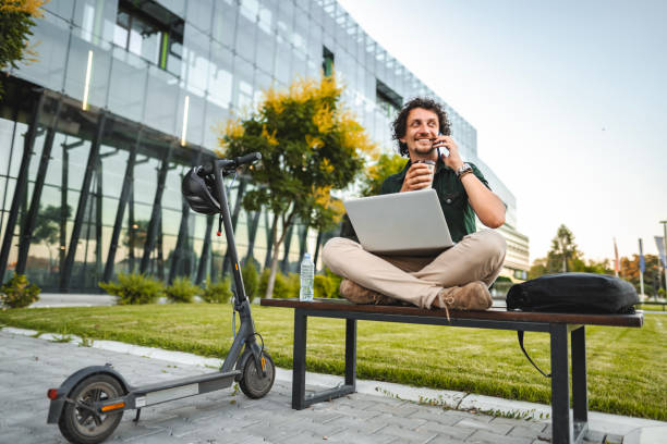 Men talking on the phone and drinking coffee while taking a break from working in public park