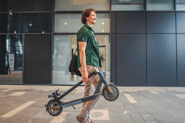 istock Man carrying his folded electric scooter in one hand while leaving work 1511480009