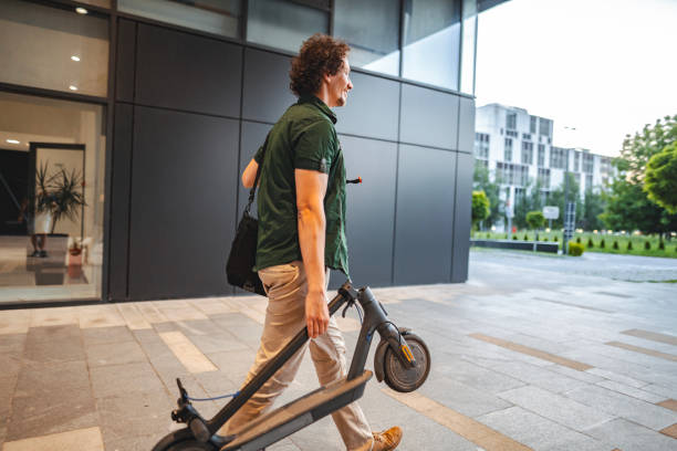 istock Man carrying his folded electric scooter in one hand while leaving work 1511482814