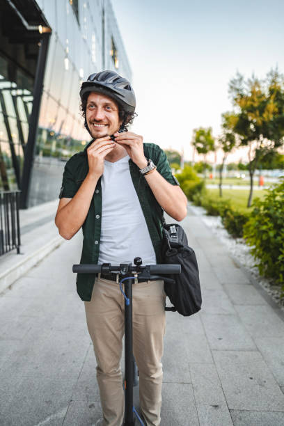 istock Man putting on protective helmet before leaving office building on his e-scooter 1511483901