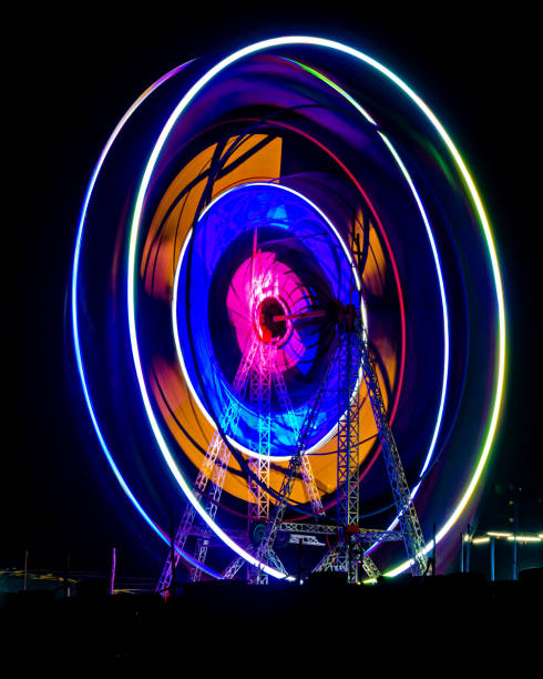 imagem lenta do obturador de uma roda-gigante colorida girando girando à noite em funfair - ferris wheel carnival wheel amusement park ride - fotografias e filmes do acervo