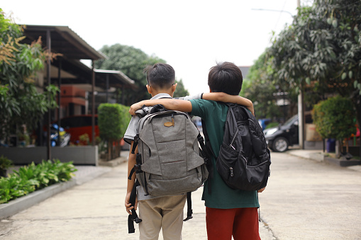 Rearview of schoolboy wearing backpack