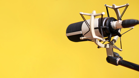 Close up of a modern microphone against yellow background