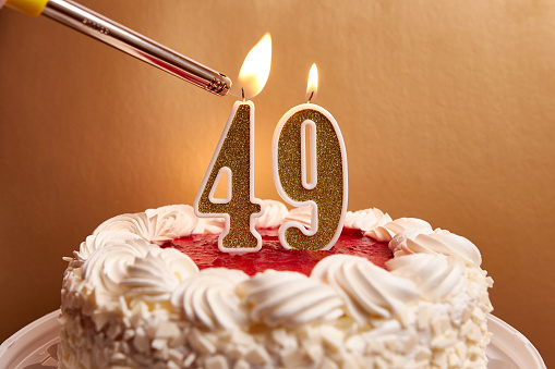 A candle in the form of the number 49, stuck in a festive cake, is lit. Celebrating a birthday or a landmark event. The climax of the celebration.