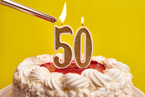 A candle in the form of the number 50, stuck in a festive cake, is lit. Celebrating a birthday or a landmark event. The climax of the celebration.