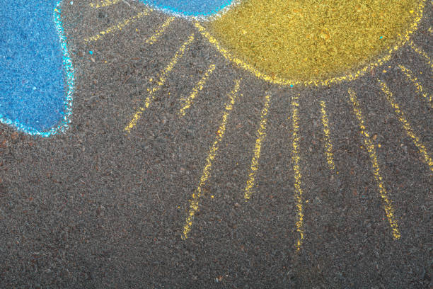 Patriotic abstract background. Hand drawing chalk picture on asphalt of a yellow sun and blue cloud. Stop war in Ukraine concept.