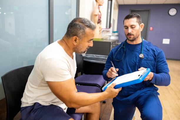 A male nurse showing a man how to fill his paperwork for the doctor appointment stock photo