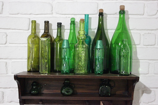 Several different shaped, vibrant blue, empty decorative vases, side by side on a shelf , in front of a window frame. Close up photo. Middle 4 vases  are of main focus in the frame.