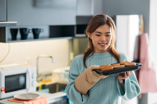 felicidade na cozinha: cupcake delicioso de uma mulher sorridente, empreendimento culinário de um empreendedor de pequenas empresas - asian ethnicity chef fine dining creativity - fotografias e filmes do acervo