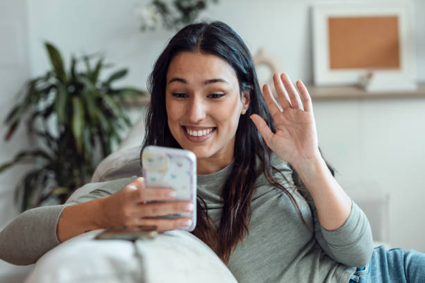 istock Beautiful woman having video conversation with friend while using her smartphone sitting on sofa at home. 1511654073