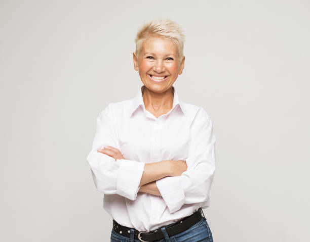 istock Mature elderly woman standing standing with arms folded over grey background. 1511661414