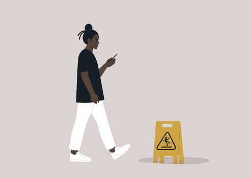 Young African character distracted by their smartphone ignoring a yellow wet floor caution sign on their way