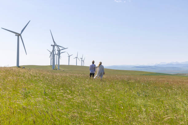 istock Couple relax in meadow below wind turbines 1511699301