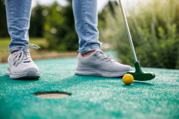 istock Woman playing mini golf and trying putting ball into hole 1511708263