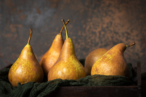 Fresh pears in male hands. Juicy flavorful pears in box, basket. Organic fruit for food or pear juice. Healthy food. Pear harvest.