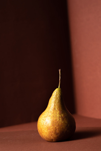 Fresh pear with shadow on brown background