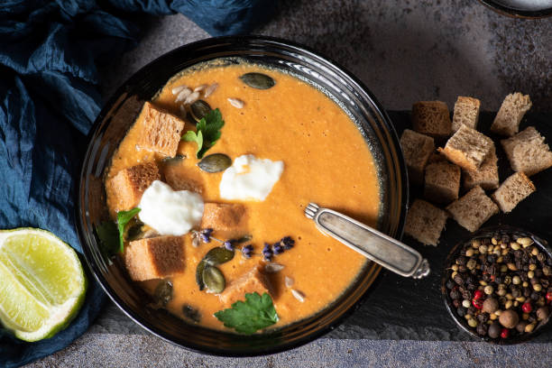 sopa de calabaza servida en un tazón con picatostes, semillas de calabaza y aceite de oliva. - pumpkin soup soup cup pumpkin fotografías e imágenes de stock