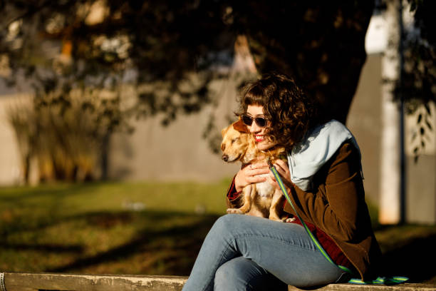 istock Short haired woman sitting on a bench while holding her pet dog 1511724235