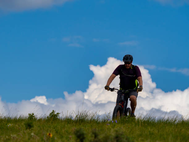 istock Mountain biker rides over meadow 1511748015
